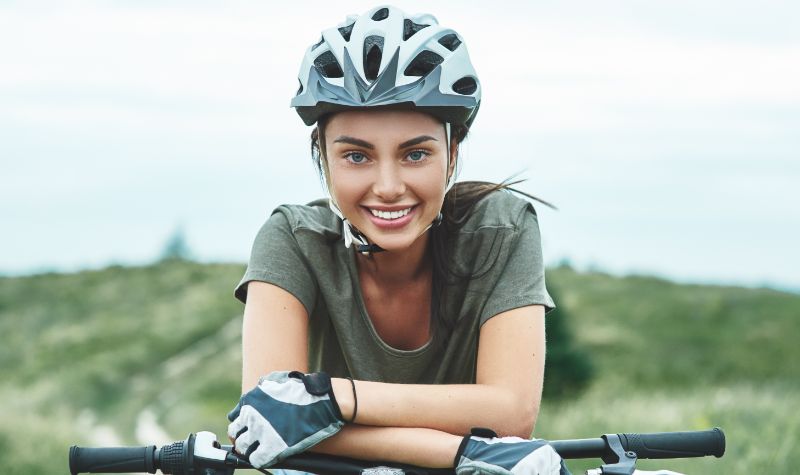 Młoda uśmiechnięta dziewczyna w kasku na wycieczce rowerowej | Hemorigen femina